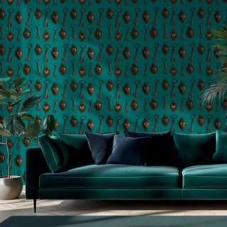 pattern of keys and metal sacred hearts on a teal background shown as wallpaper with sofa and plants